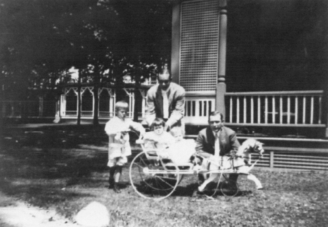 Middle Bass Club: Member Jay Secor and children in a toy carriage in front of the Middle Bass Club House. Toledo Public Library.