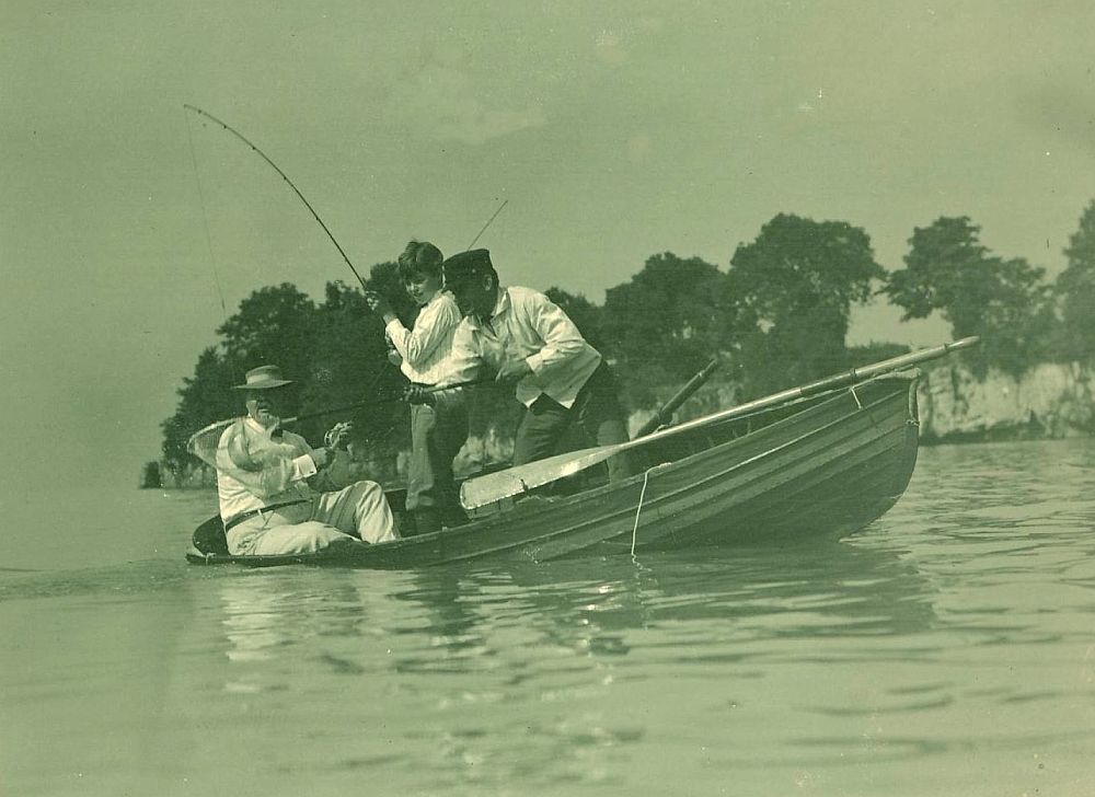 Charlie Taft fishing reeling in a fish from a rowboat